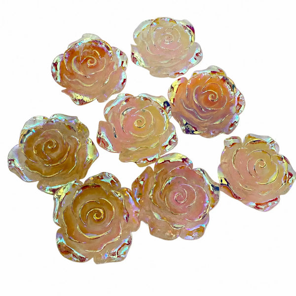 A set of eight rose-shaped craft beads with an iridescent, holographic finish. The beads feature a soft pink and peach 