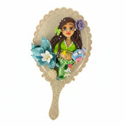 Angled view of a custom hand mirror embellished with a flexible cold porcelain pregnant mermaid and a purple flower