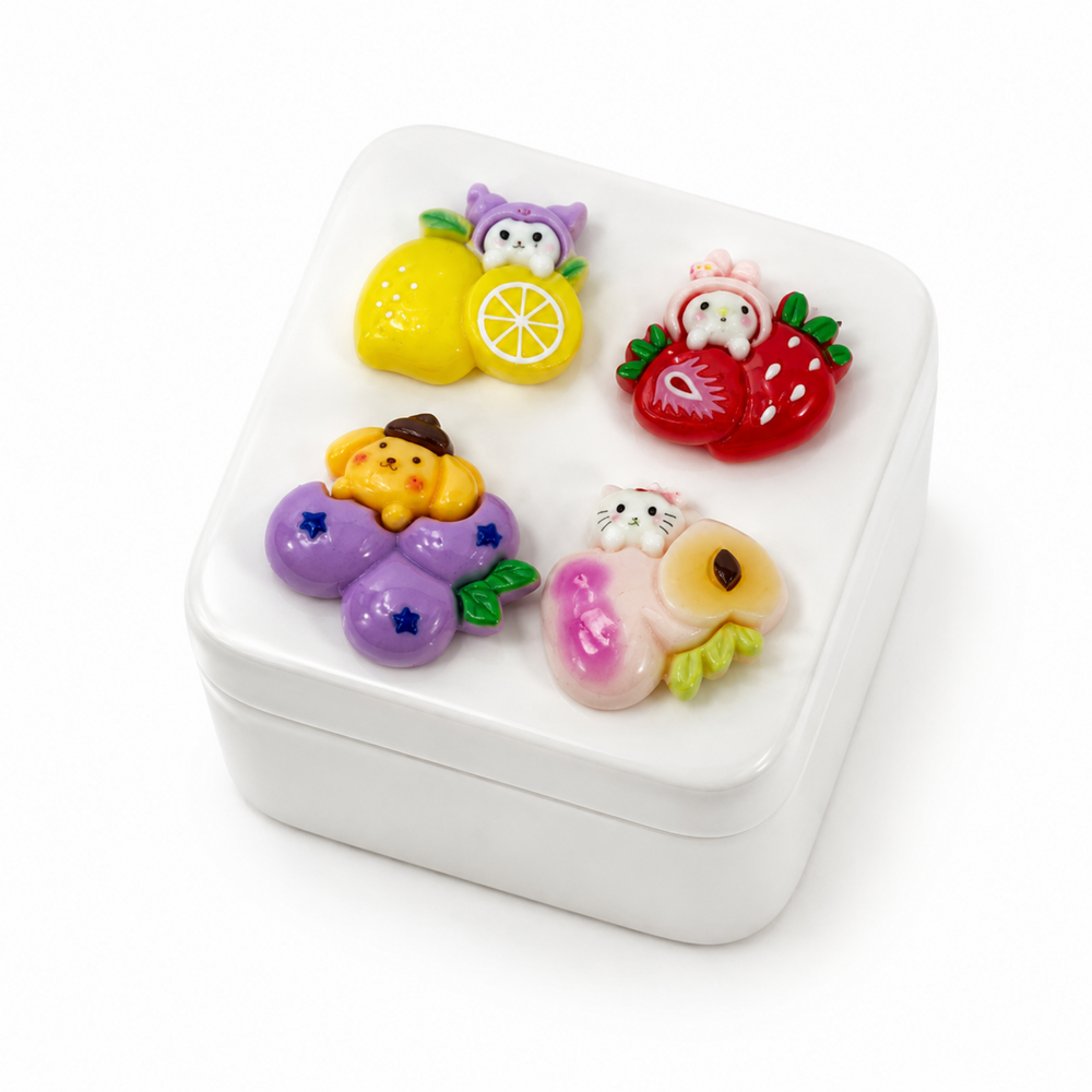 Assorted fruit-themed resin flatbacks decorating a phone case and notebook
