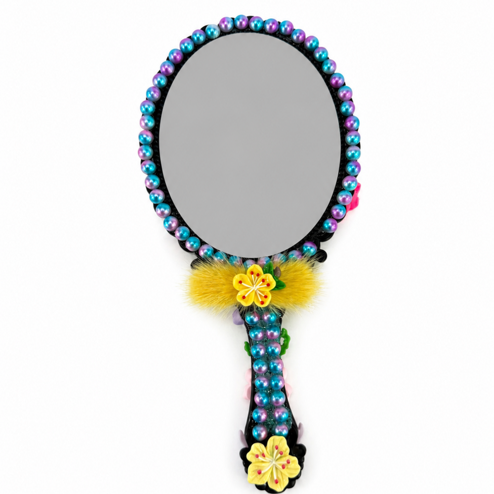 Back of decorated mermaid hand mirror with colorful beaded border, floral handle and gray mirror surface