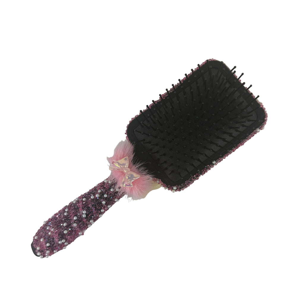 Back view of a black hair brush showing the detailed handmade fuchsia sparkling design on the handle and base