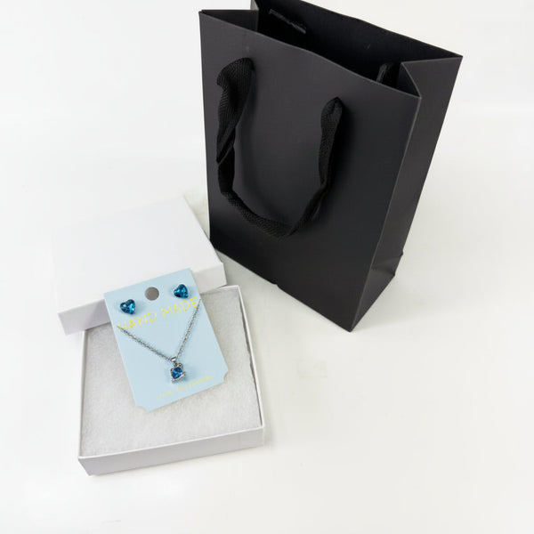 Blue heart jewelry gift set with crystal heart stud earrings, matching necklace, white gift box, and black gift bag