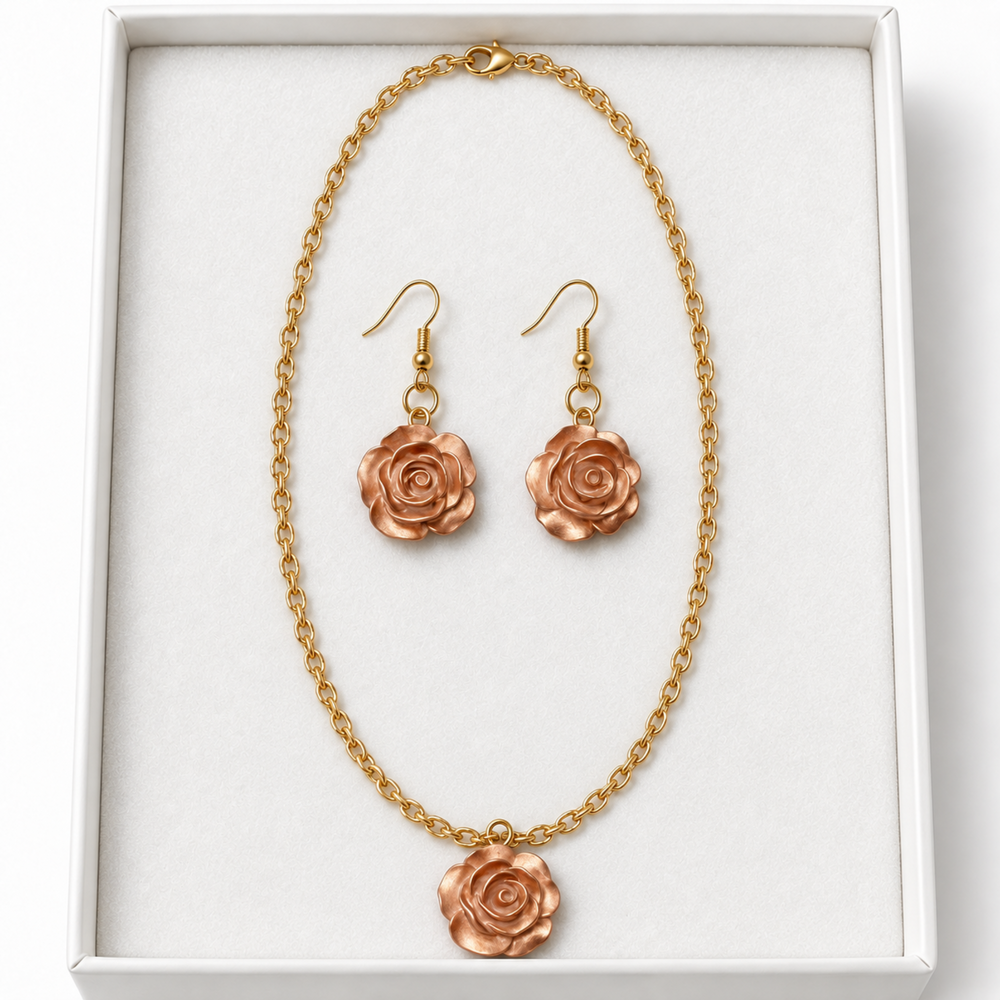 Close-up of a champagne rose necklace and matching hook earrings arranged on soft white velvet inside a jewelry box.