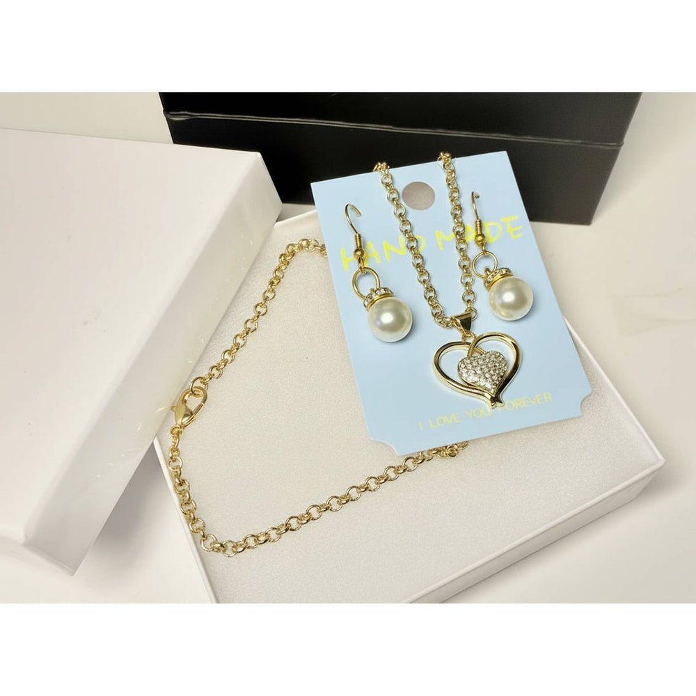Close-up of gold tone heart pendant necklace and faux pearl drop earrings set
