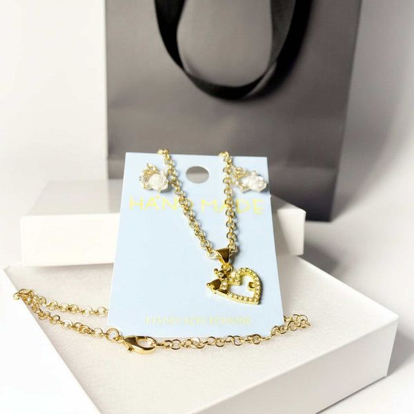 Close-up of gold tone heart pendant necklace and rose drop earrings set
