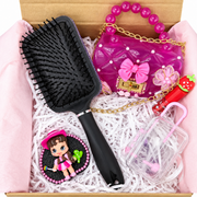 Close-up of pink cowgirl clay figure on black glitter base with pearl trim beside a decorated black hairbrush handle.
