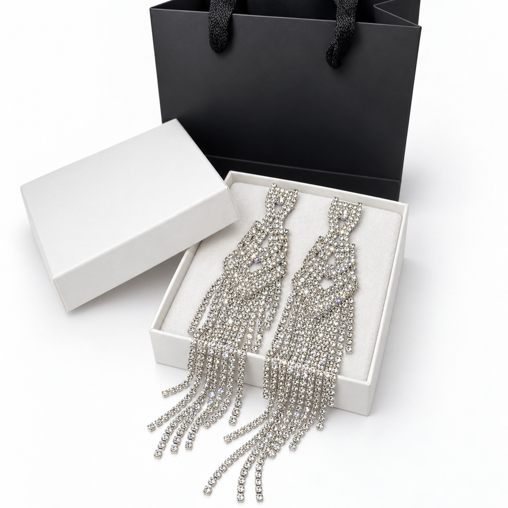 Close-up of silver rhinestone earrings with open geometric details and cascading crystal strands