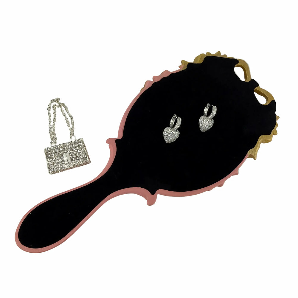 Close-up of silver rhinestone purse charm and crystal heart earrings from the Glam & Glow self-care gift box