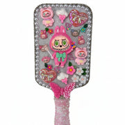 Close up of a decorated paddle brush with a cute pink monster, heart bow, butterfly, and shimmering finish.