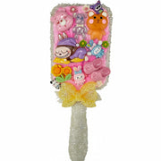 Close up of a decorated paddle brush with pink cream backing, mini pink crocs charms, butterfly, and heart details