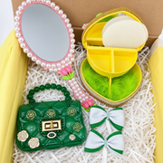 Coordinated handmade gift set with pink floral mirror, yellow heart trinket box, green handbag, two bows, and matching necklace and earrings in an open box.