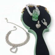 Crystal anklet, heart earrings, and handmade charm keychain displayed on a vintage handheld mirror