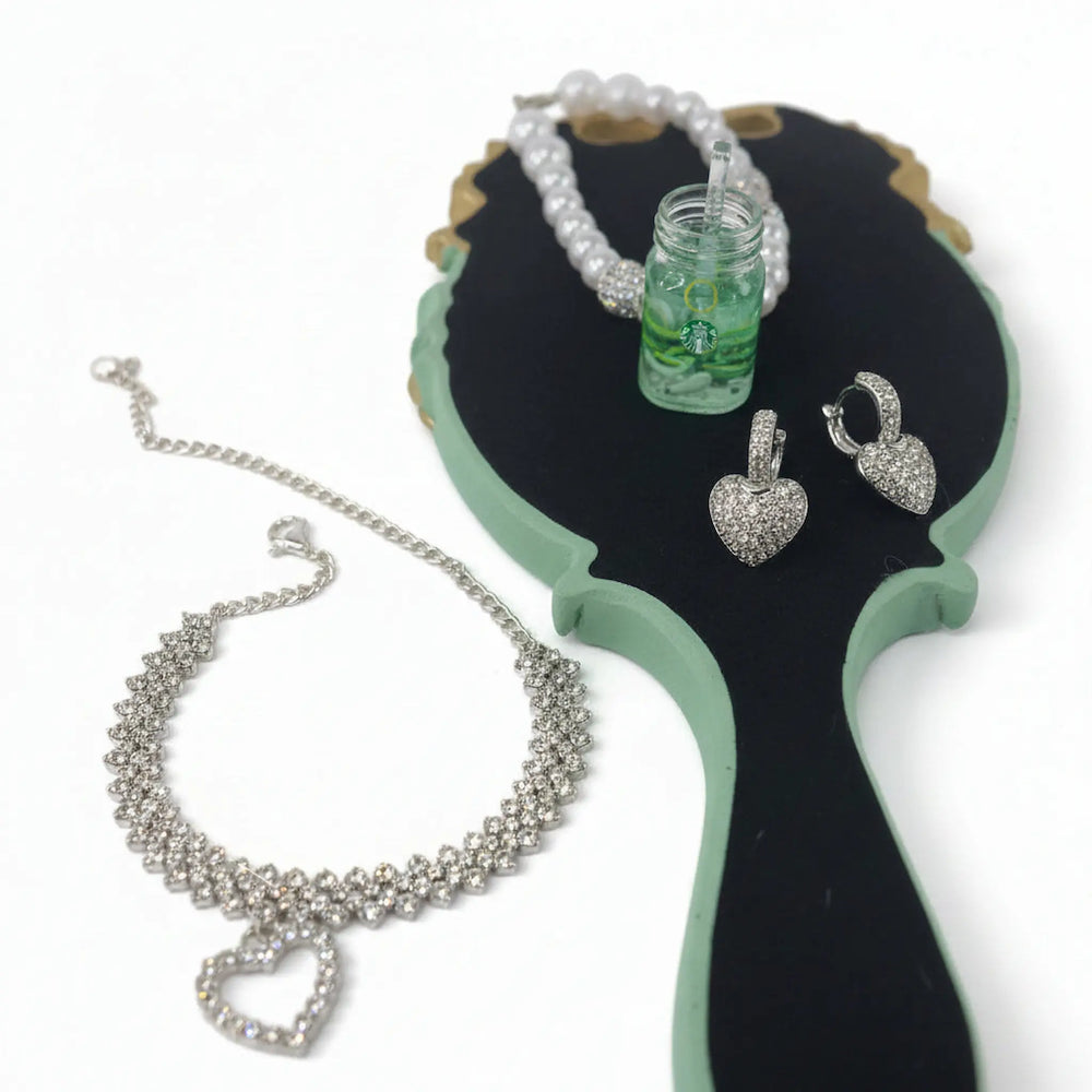 Crystal anklet, heart earrings, and handmade charm keychain displayed on a vintage handheld mirror