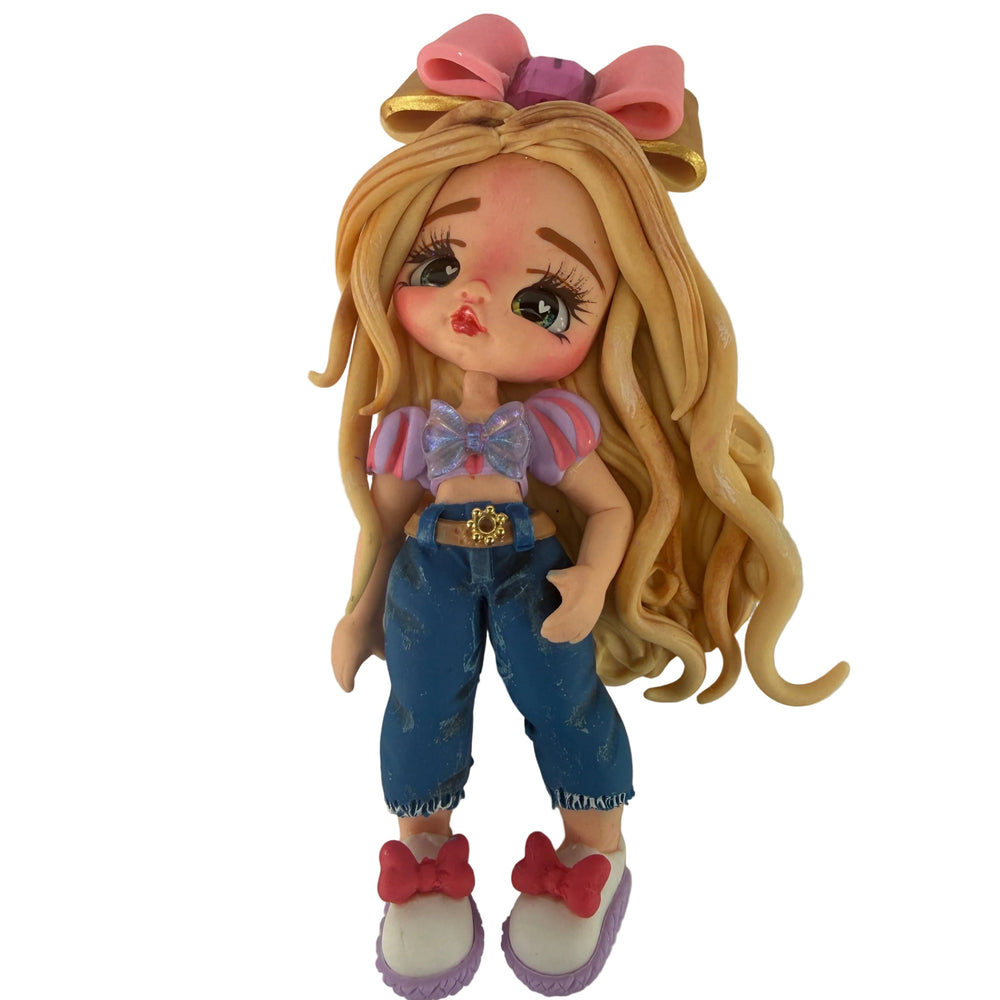 Front view of a handmade flexible cold porcelain blonde doll planar with long wavy hair, pink bow, and denim outfit for DIY crafts