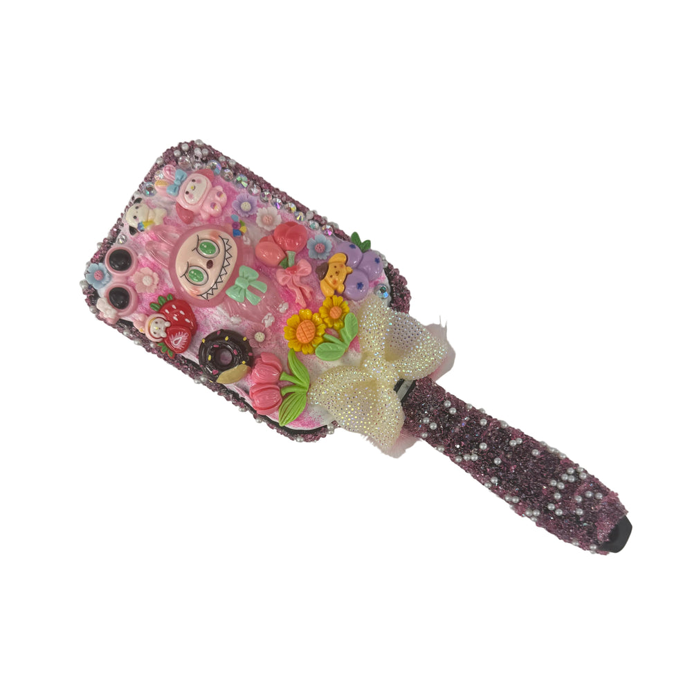 Handmade black monster decoden hair brush with a sparkling fuchsia cream background, white bow, and cute pink charms