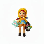 Handmade flexible porcelain garden girl doll charm with red hair, a yellow hat, green watering can, and rose basket