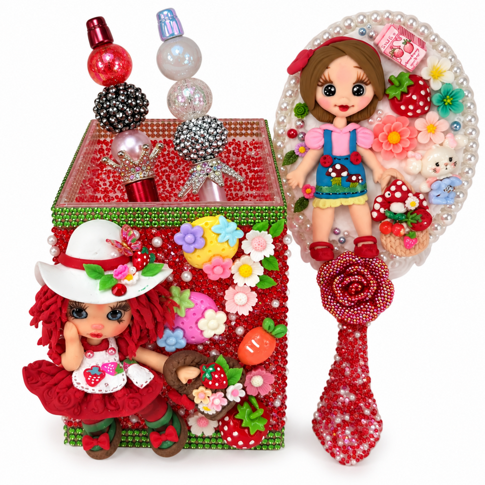 Handmade strawberry pencil holder decorated with rhinestones, flowers, fruit charms, and a red-haired doll in a white hat.
