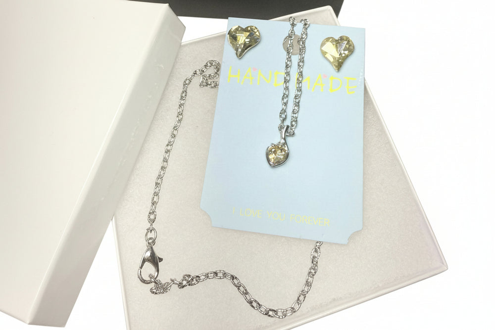 Heart crystal necklace and earring jewelry set displayed in a white gift box with a luxury black gift bag