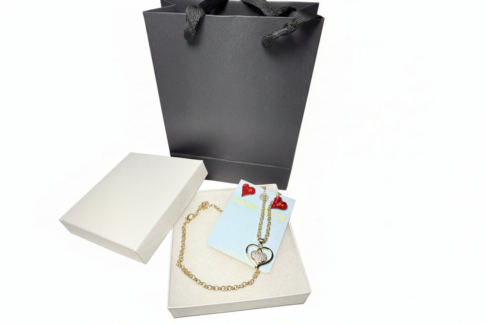 Red crystal earrings and gold-tone heart pendant necklace displayed in a white gift box with a luxury black gift bag