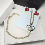 Red crystal earrings and gold-tone heart pendant necklace displayed in a white gift box with a luxury black gift bag and red heart crystal earrings