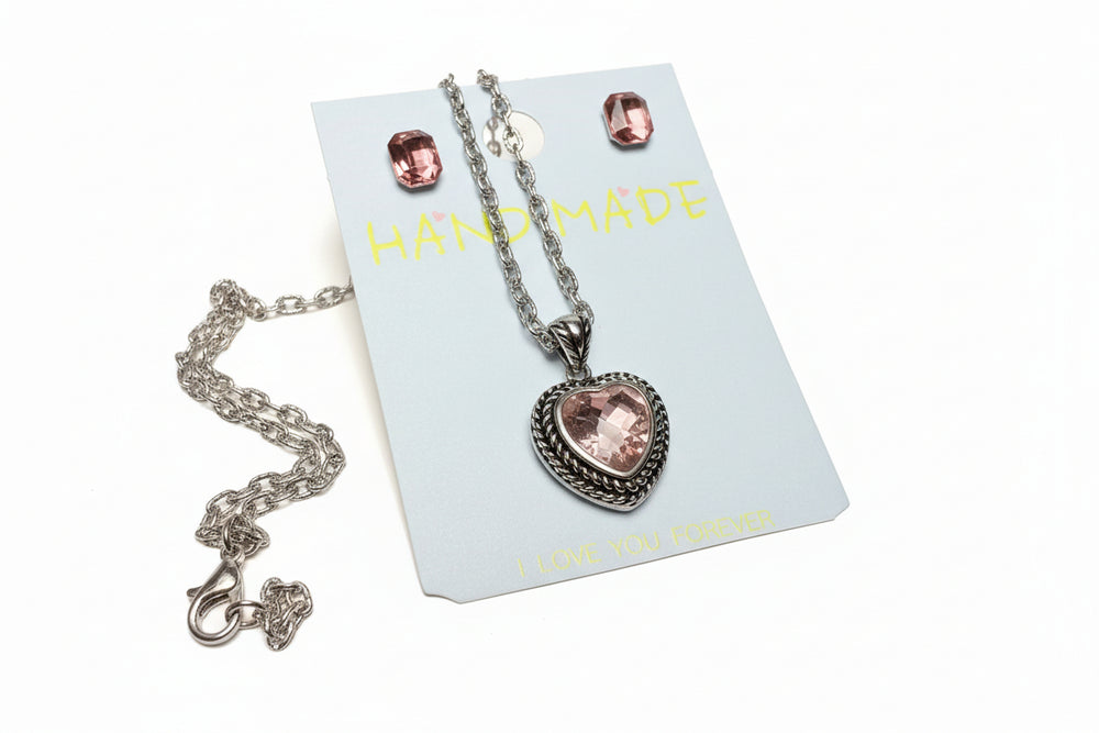 Close-up of a sparkling heart crystal pendant necklace on a "Hand Made" jewelry display card