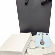 Close-up of a sparkling pink heart pendant necklace and crystal earring set, on a white jewelry card, displayed with a premium gift box