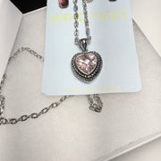 Heart-shaped pendant necklace and earrings on a 'Handmade' card with a white background