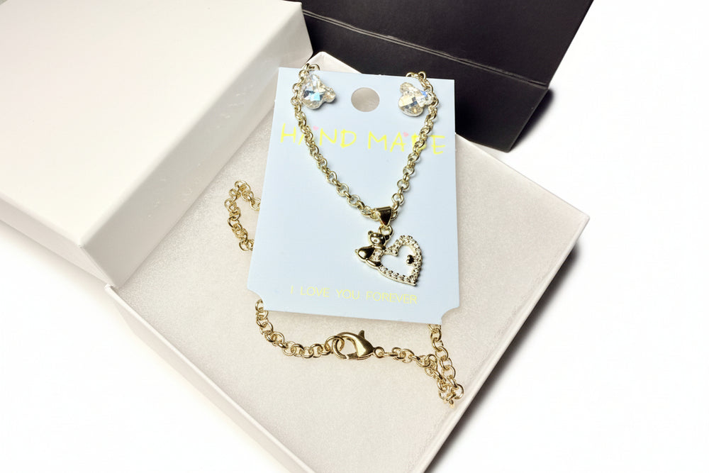 Majestic Boutique presentation: Heart and teddy bear jewelry set in a white box with a black luxury handle bag and tissue paper.