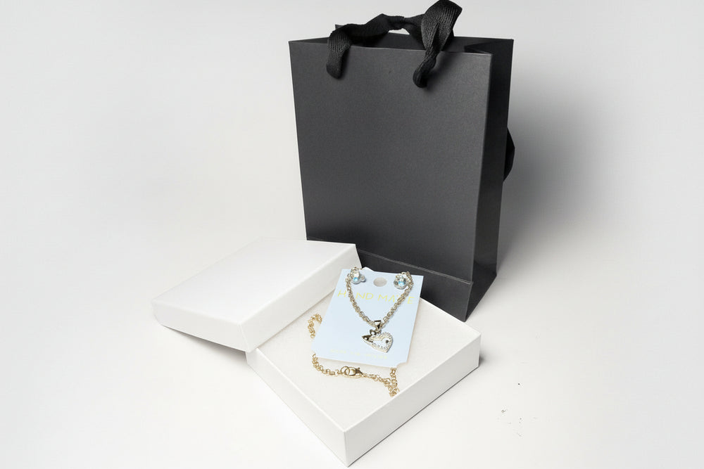 Close-up of sparkling crystal teddy bear earrings and rhinestone heart pendant on a 'Handmade' jewelry card.