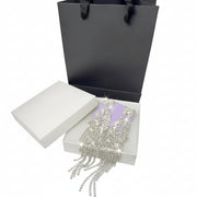 Luxury silver rhinestone drop earrings presented in a white jewelry gift box with an elegant black paper bag