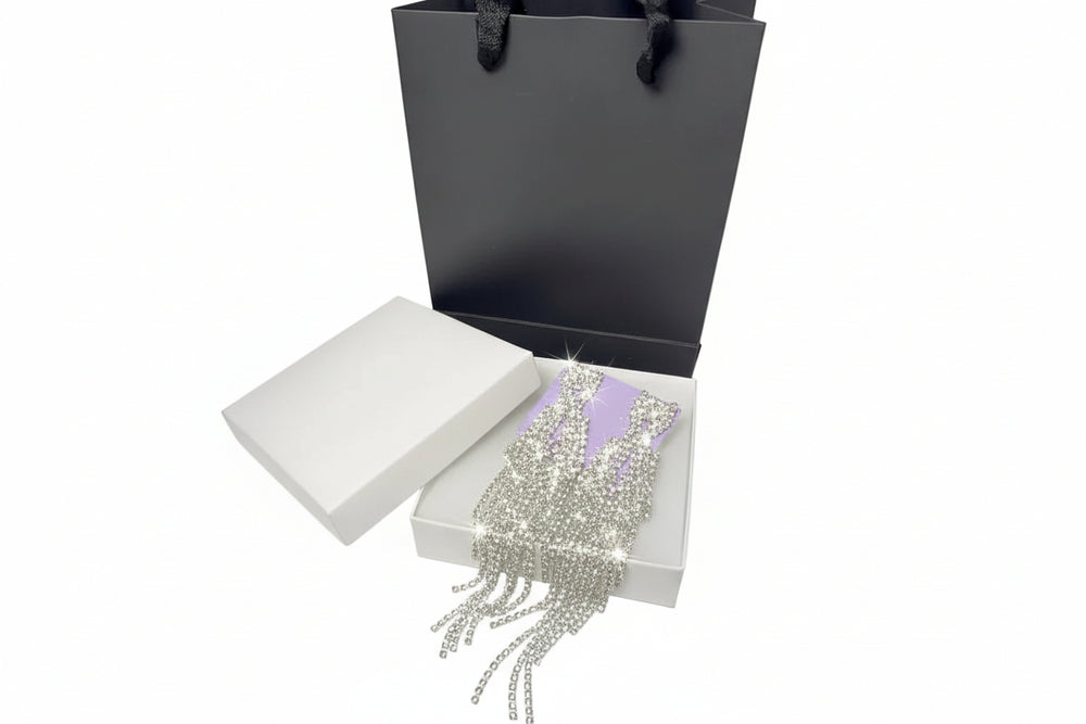 Luxury silver rhinestone drop earrings presented in a white jewelry gift box with an elegant black paper bag