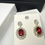 Close-up of luxury red gemstone drop earrings featuring brilliant crystal accents and gold-tone finish.'

