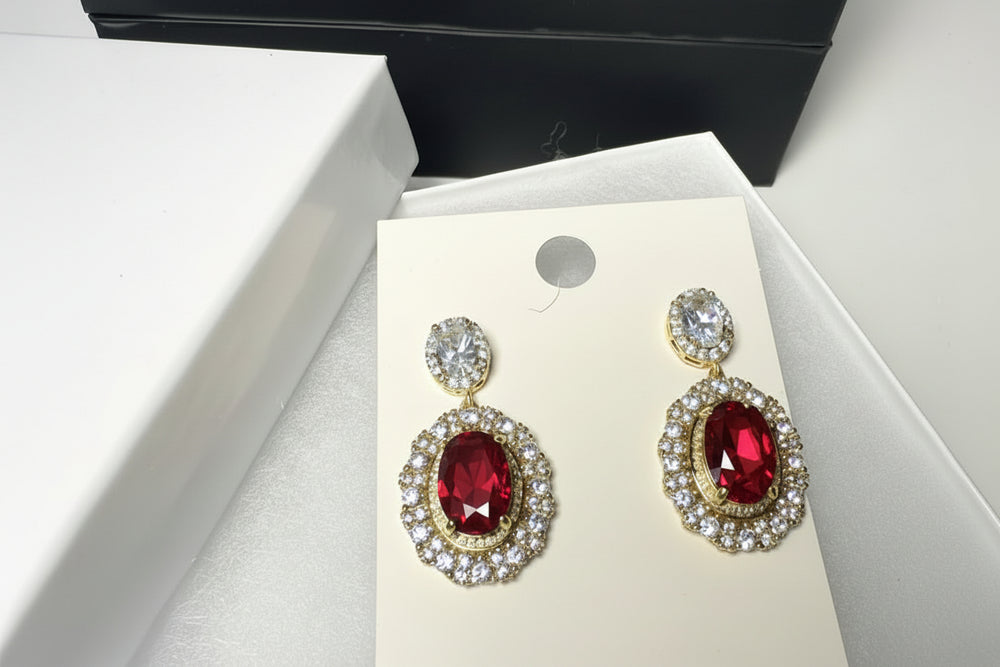 Close-up of luxury red gemstone drop earrings featuring brilliant crystal accents and gold-tone finish.'

