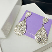 Close-up of sparkling teardrop statement earrings with high-quality crystals and silver-tone finish for weddings.'