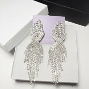 Close-up of sparkling silver-tone teardrop earrings on a white jewelry box - Premium detail