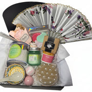 Luxury teal and gold spa gift basket for women featuring a designer hand fan, aromatic candle, bath bombs, and a ceramic bowl set in a premium birthday arrangement.