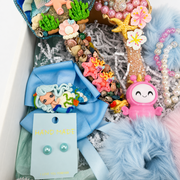 Mermaid gift set with decorated mirror, hair brush, blue bow, bracelets, earrings, and fluffy accessories.