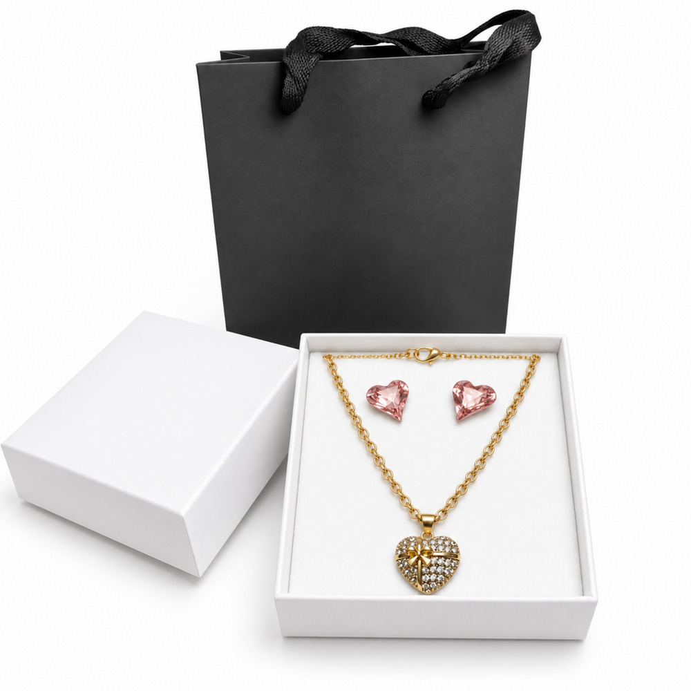Pink crystal heart earrings and rhinestone heart necklace in a white jewelry box with a black gift bag.