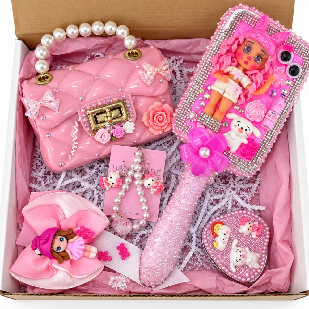 Pink gift box set featuring a decorated pearl-handle purse, rhinestone hairbrush, pink bow, pearl bracelets, and sparkly heart accessory arranged with pink tissue paper.