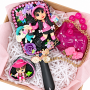 Pink gift box with black hairbrush, purple mini purse, clear mini suitcase, lip gloss, and pink clay cowgirl accent.