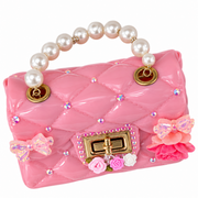 Pink quilted purse with a glossy finish, large pearl handle, gold-tone clasp, delicate bow accents, rhinestones, and small pink floral details on the front.