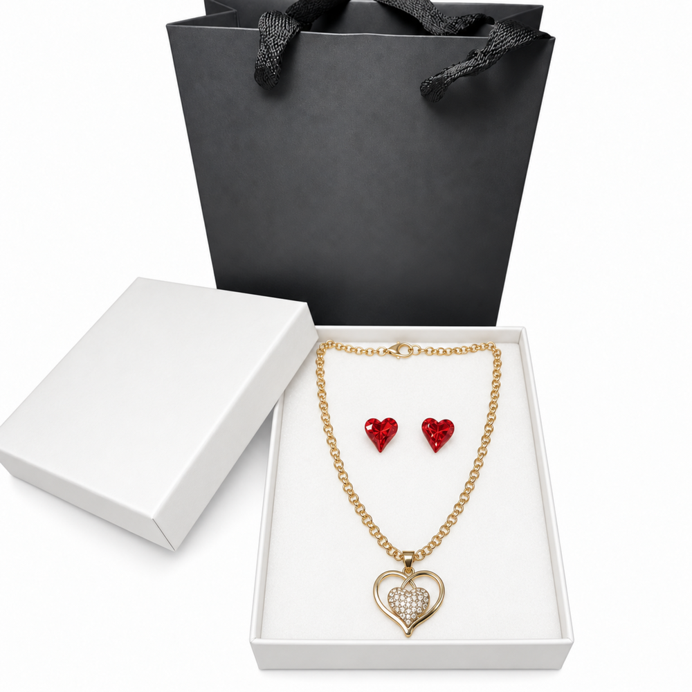 Red crystal heart earrings and gold-tone rhinestone heart necklace displayed inside an elegant white jewelry box.