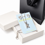 Silver-tone initial K necklace with crystal pendant and matching heart earrings displayed in an elegant white gift box.