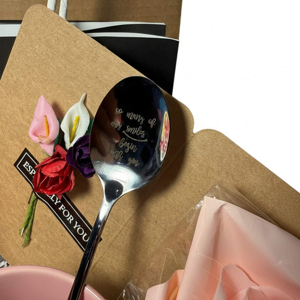 Silver spoon with a decorative card on a brown surface with flowers.