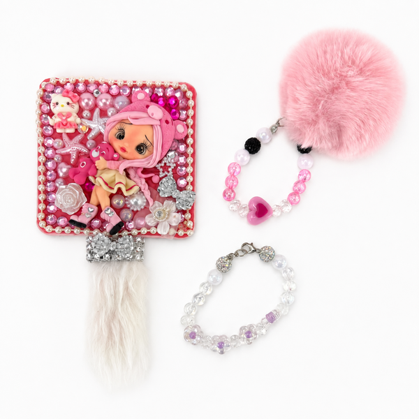Small pink hand mirror with gray reflective surface, rhinestone detail and soft white faux fur accent