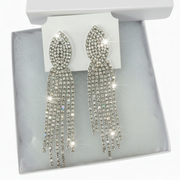 Sparkly rhinestone drop earrings presented in a jewelry box with tissue paper and gift bag.
