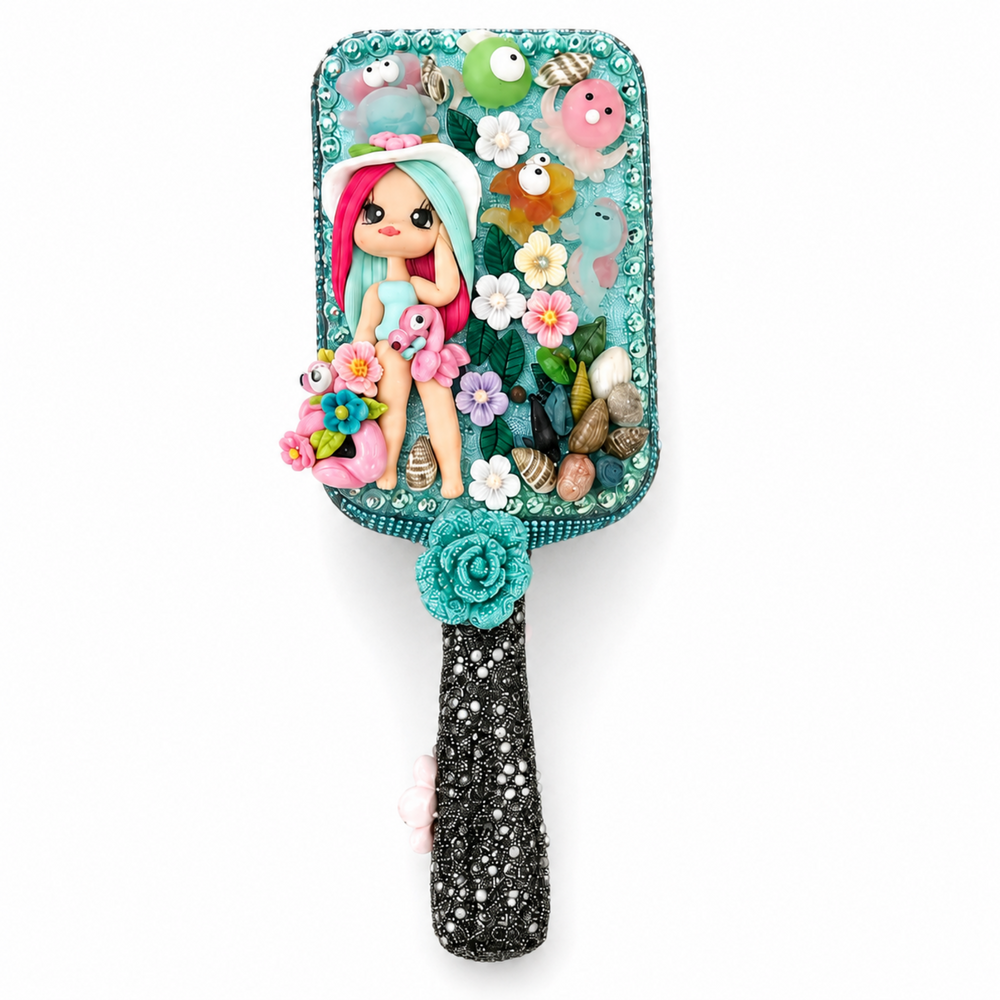 Turquoise ocean-themed hair brush and hand mirror decorated with mermaid dolls, flowers, seashells, flamingos, pearls and rhinestones.

