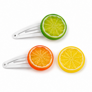 White hair clips decorated with colorful lime and orange resin citrus slice flatbacks.