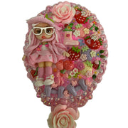 close up of a handmade decoden hand mirror heavily decorated with a cute doll figure pink roses and strawberry charms