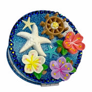 compact mirror with starfish flowers and wheel design on blue glittery background"